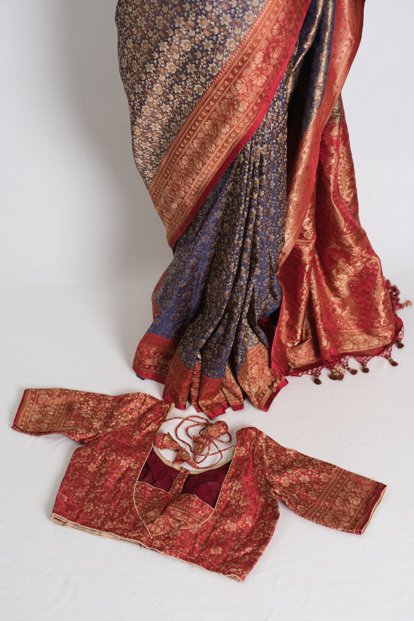 Traditional embroidered garment with a red and blue pattern on a white background