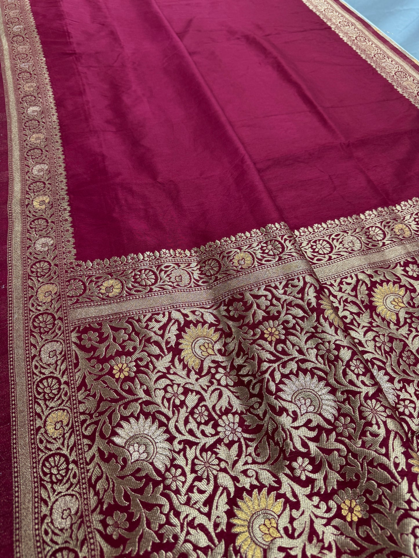 Maroon fabric with intricate gold and white embroidery