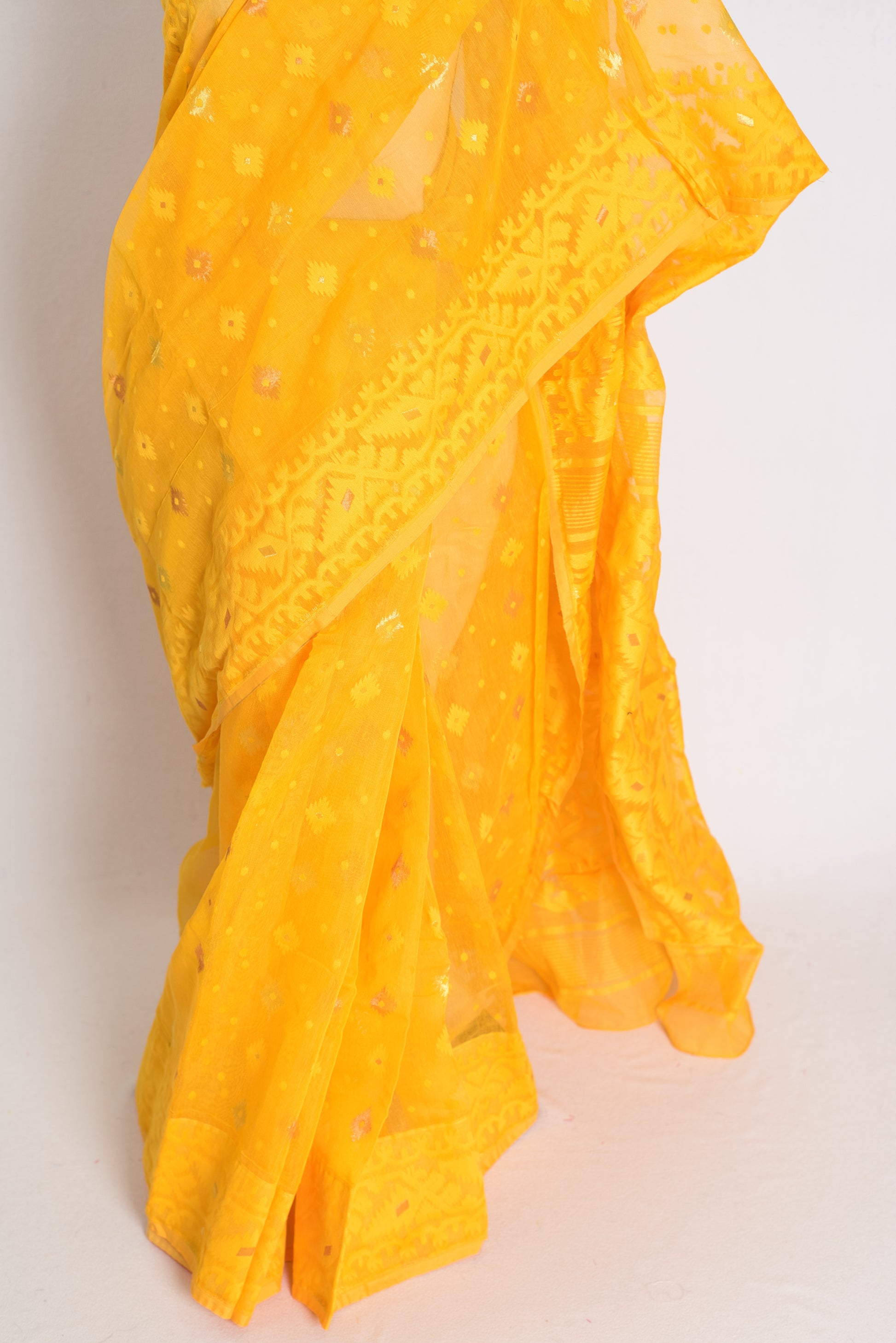 A vibrant deep yellow Bengali Jamdani saree crafted from a soft cotton blend, featuring traditional hand-loomed patterns perfect for festive occasions.