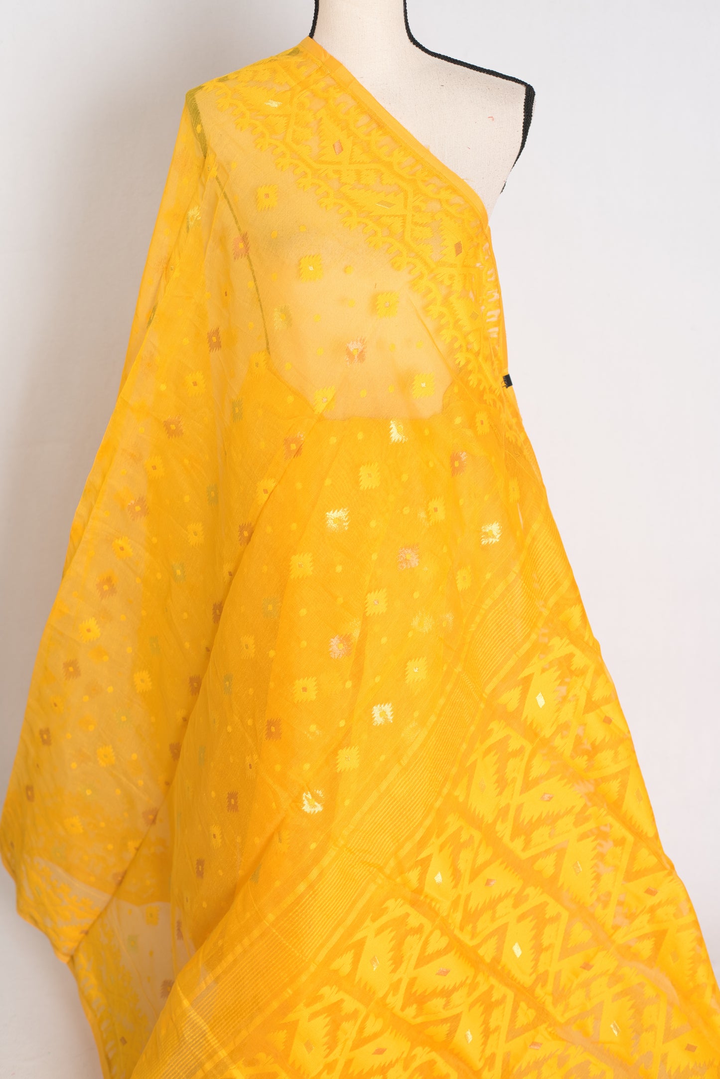 A vibrant deep yellow Bengali Jamdani saree crafted from a soft cotton blend, featuring traditional hand-loomed patterns perfect for festive occasions.