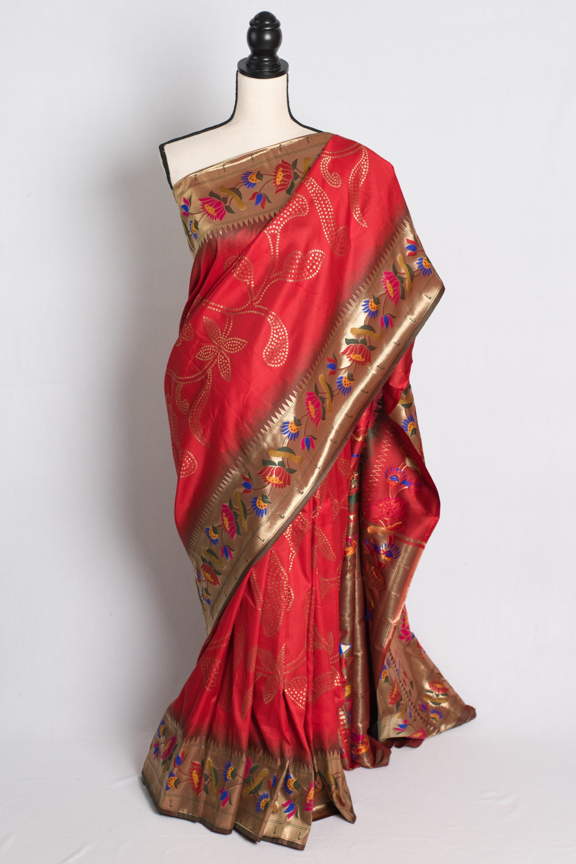 Red saree with gold border on a mannequin against a white background