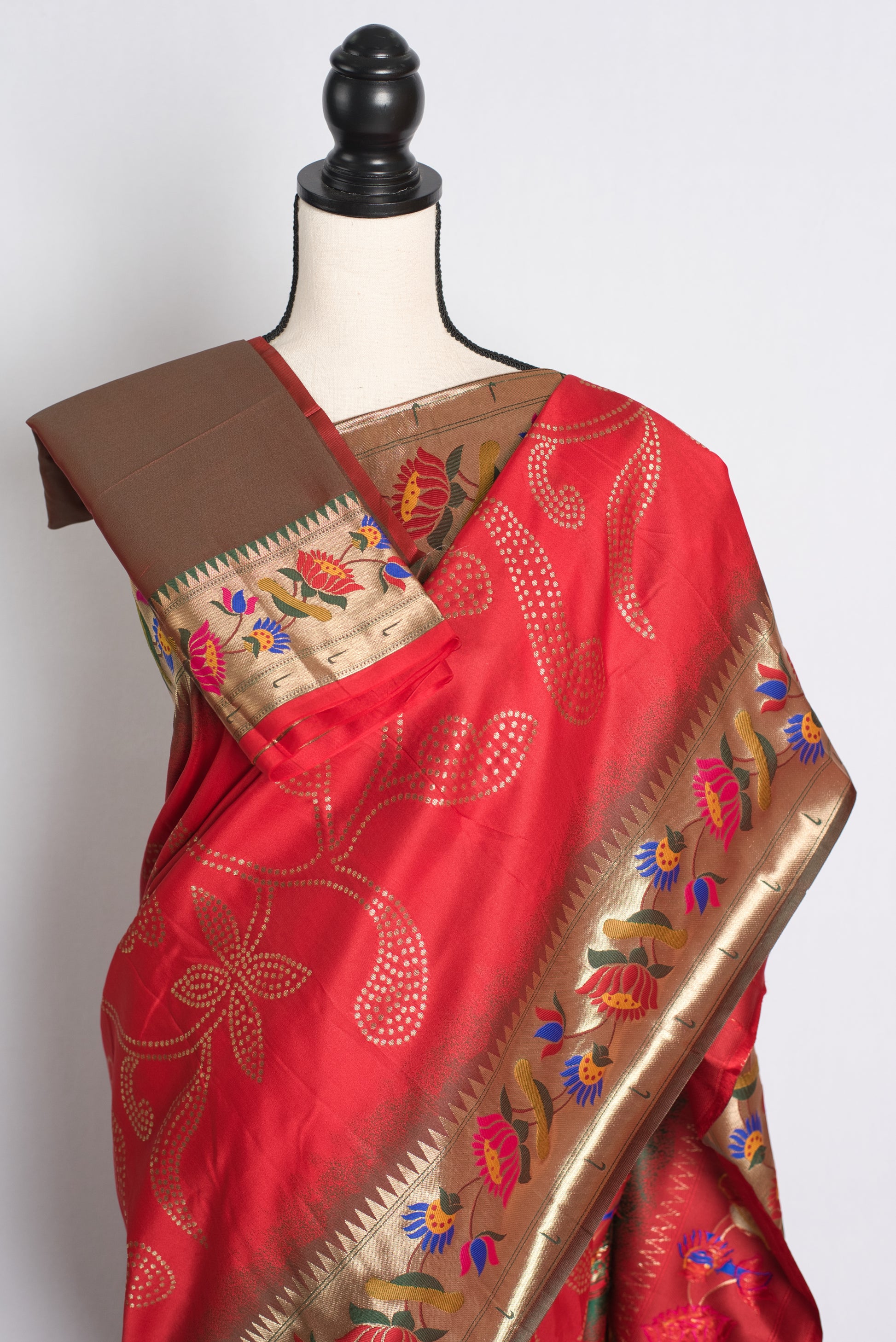 Red saree with gold border on a mannequin against a white background