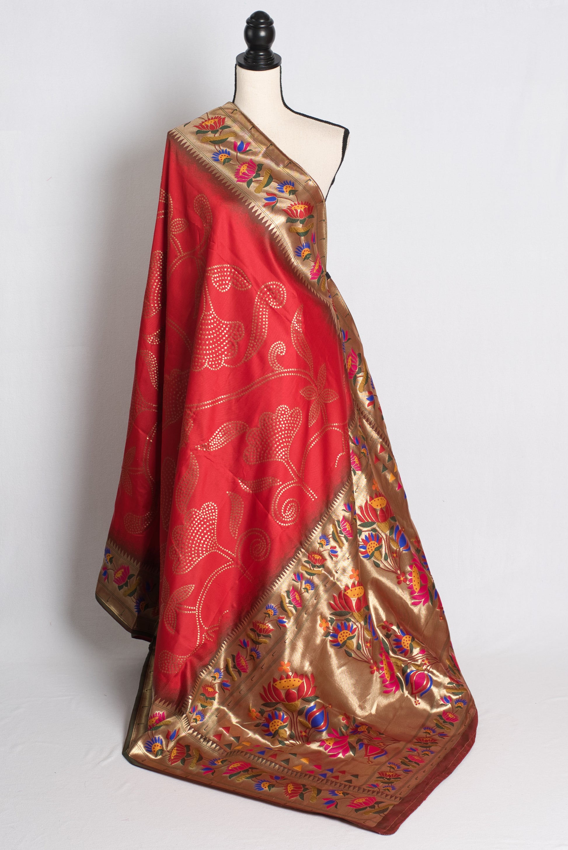 Red and gold saree with intricate patterns on a mannequin against a white background