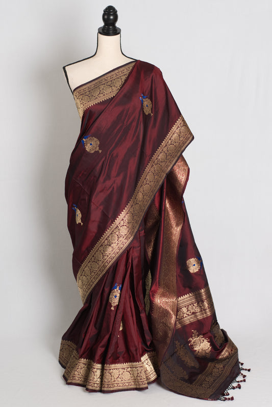 Maroon saree with gold border on a mannequin against a white background