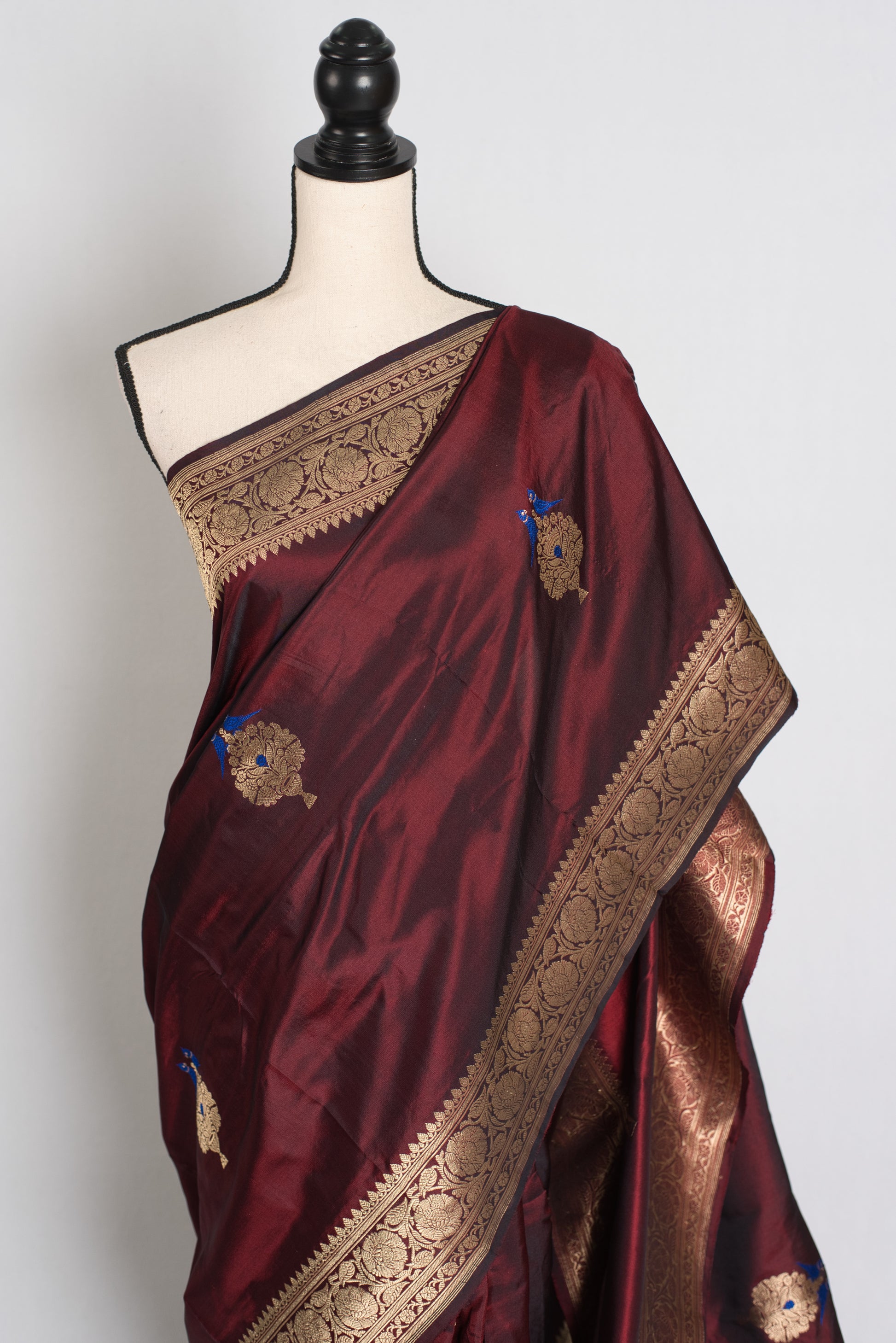 Maroon saree with gold border on a mannequin against a white background