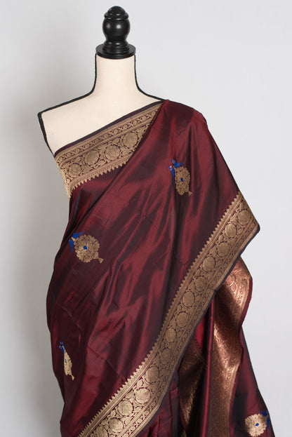Maroon saree with gold border on a mannequin against a white background