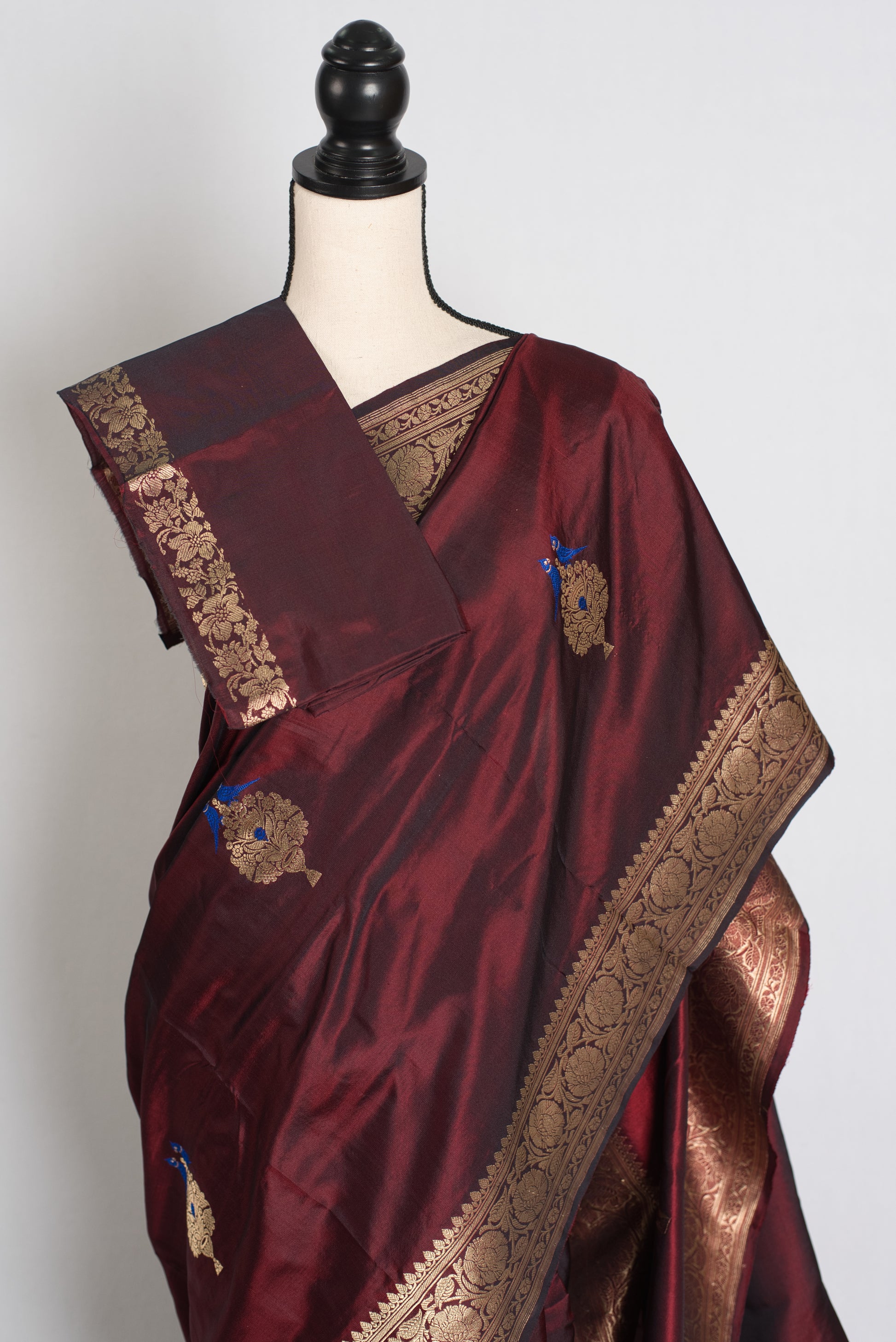 Maroon saree with gold embroidery on a mannequin against a white background