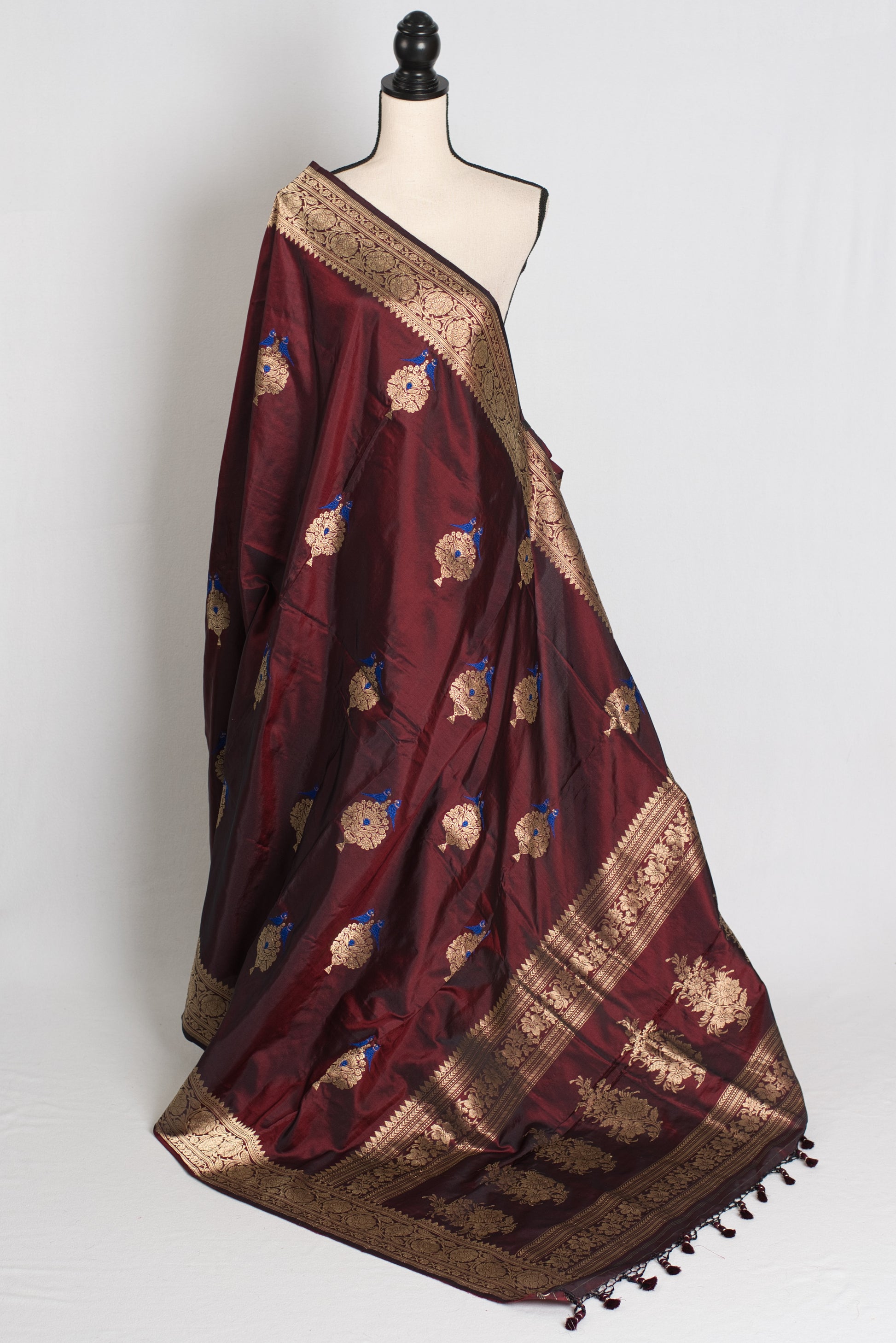 Maroon saree with gold embroidery on a mannequin against a white background