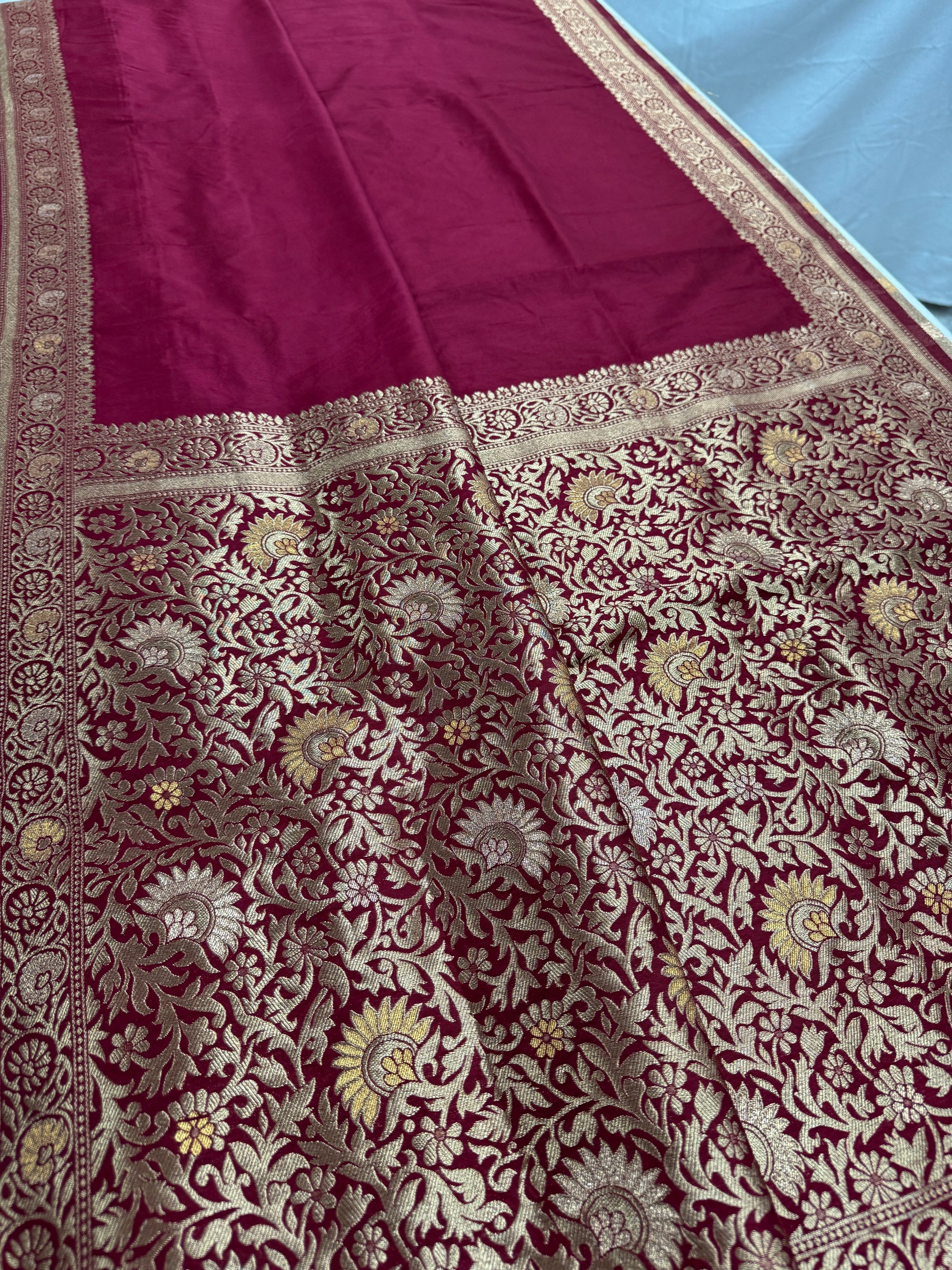 Maroon fabric with intricate gold and white floral patterns