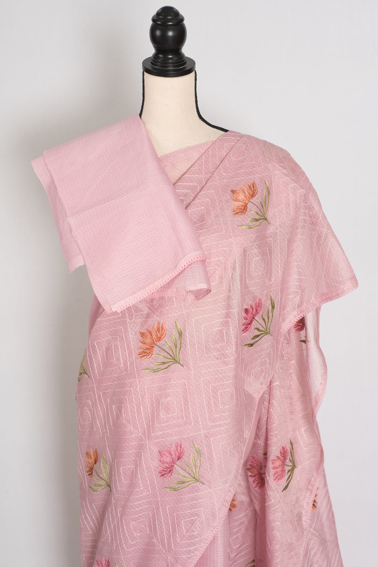 Pink saree with floral embroidery on a mannequin against a white background