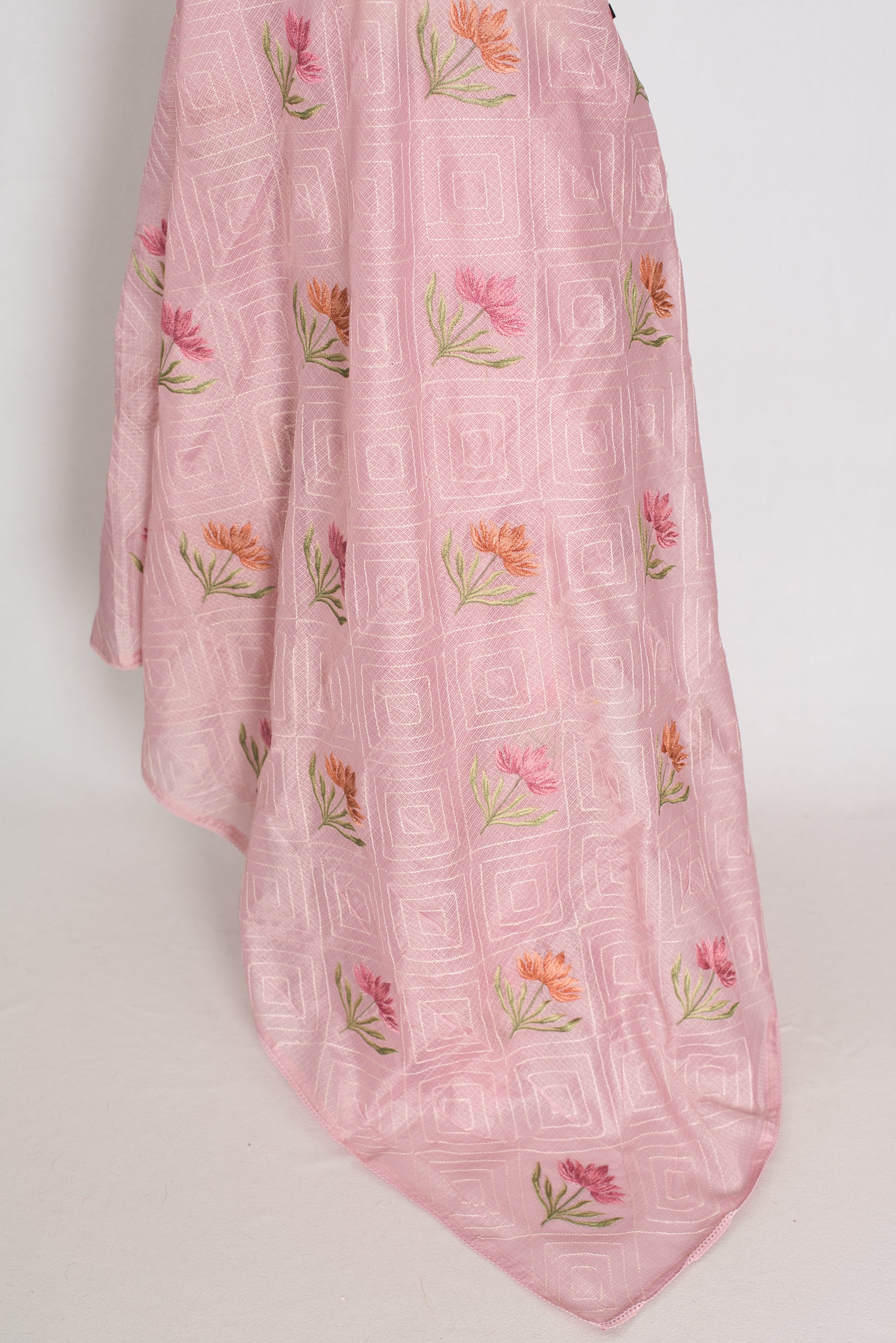 Pink fabric with floral patterns draped over a white background