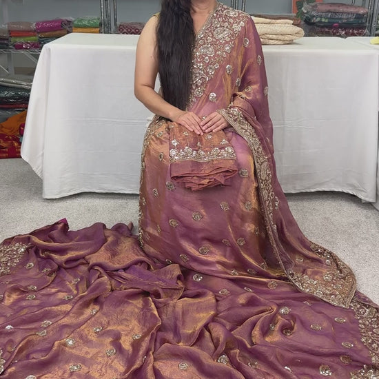 video of Soft peach purple organza partywear saree on a mannequin displaying heavy designer embroidery and metallic shimmer finish.