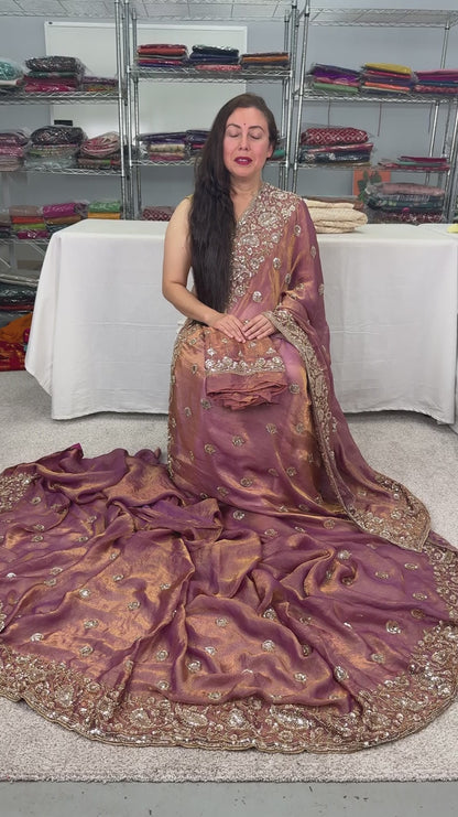 video of Soft peach purple organza partywear saree on a mannequin displaying heavy designer embroidery and metallic shimmer finish.